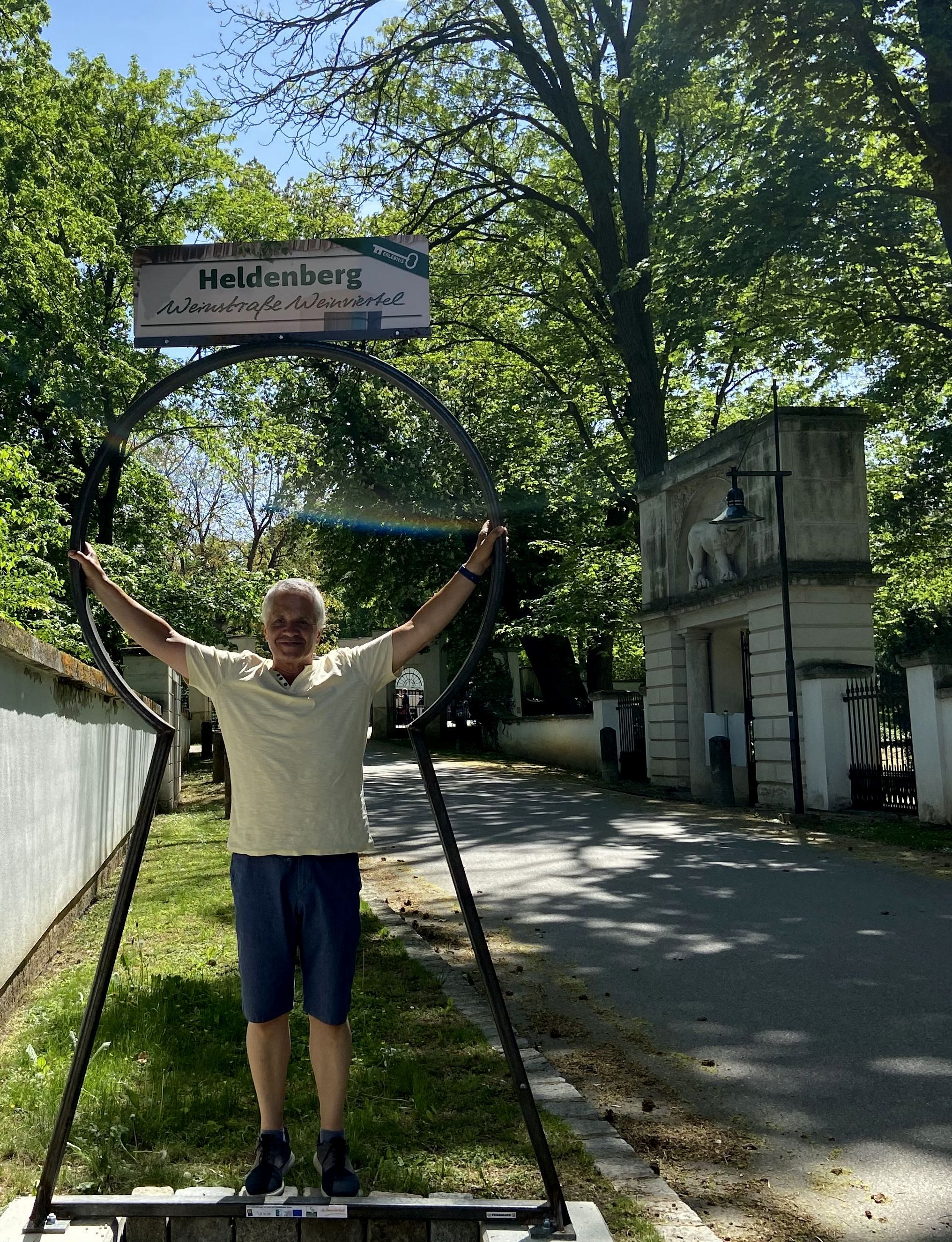 Ein Mann steht in einem großen, schlüsselförmigen Rahmen mit einem Schild "Heldenberg Weinstraße Weinviertel" darüber.