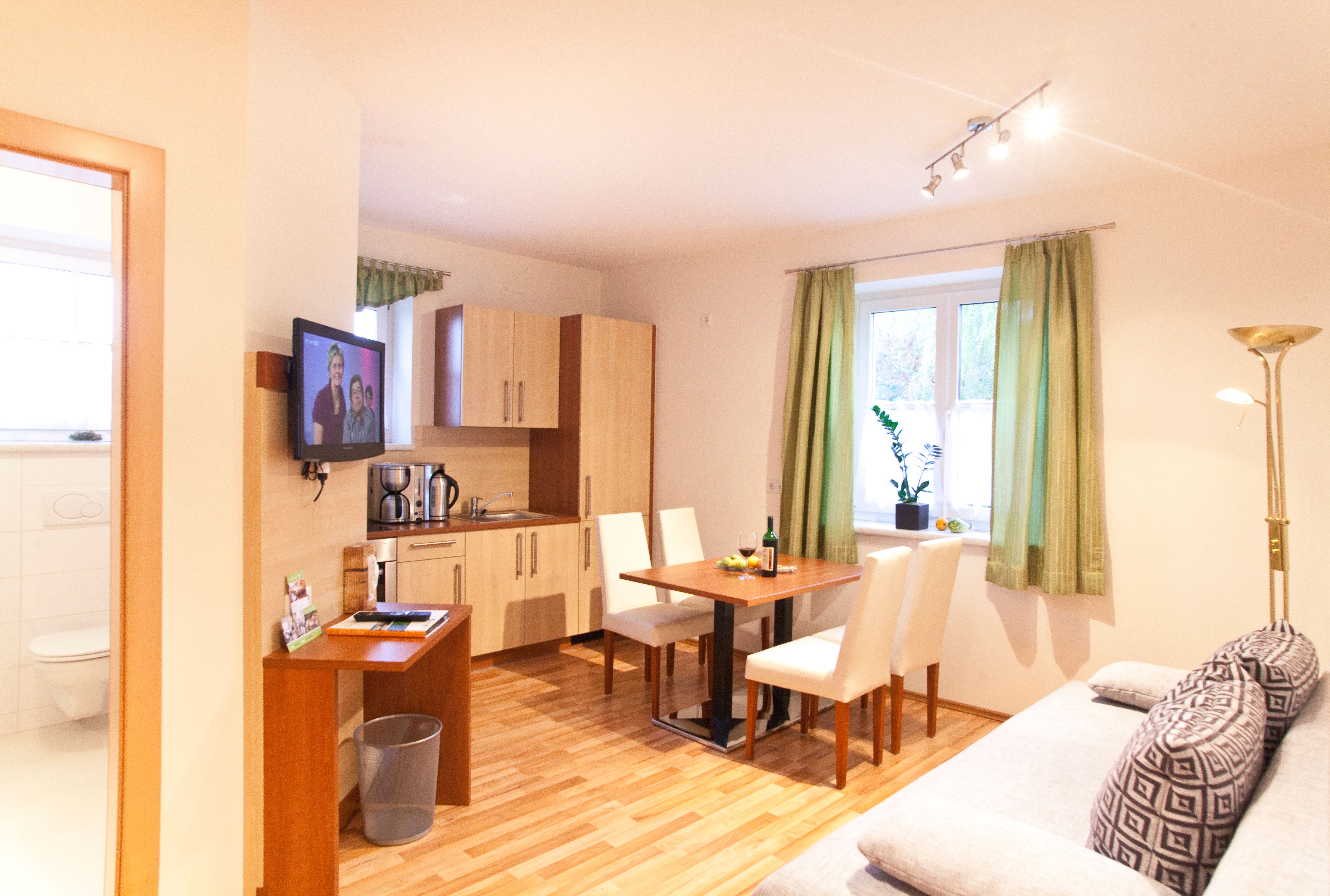 Moderne Küche mit Esstisch, Sofa und Fernseher in einem hellen Raum.