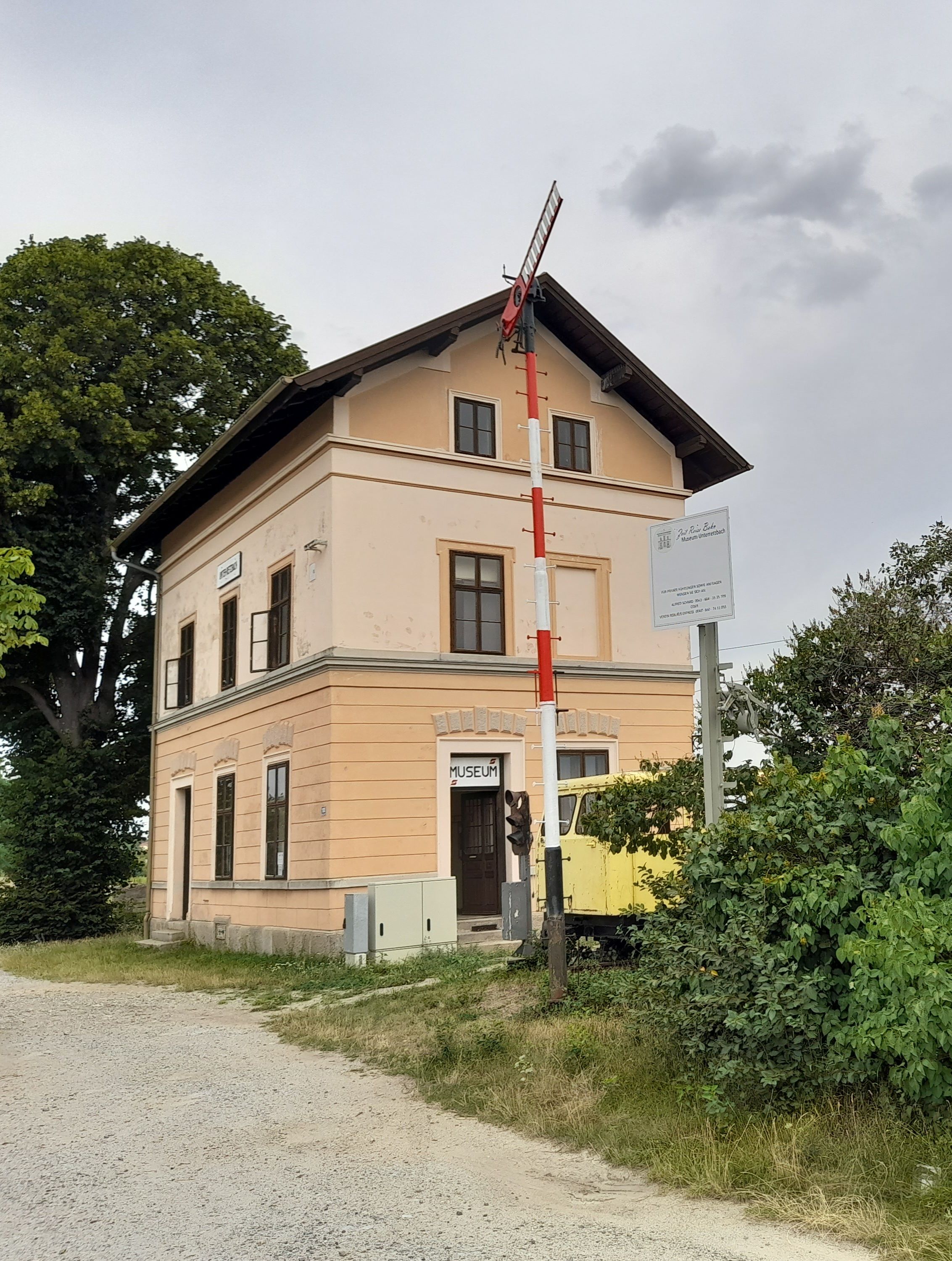 Stará nádražní budova s muzejní cedulí a návěstidlem v Unter-Retzbachu.