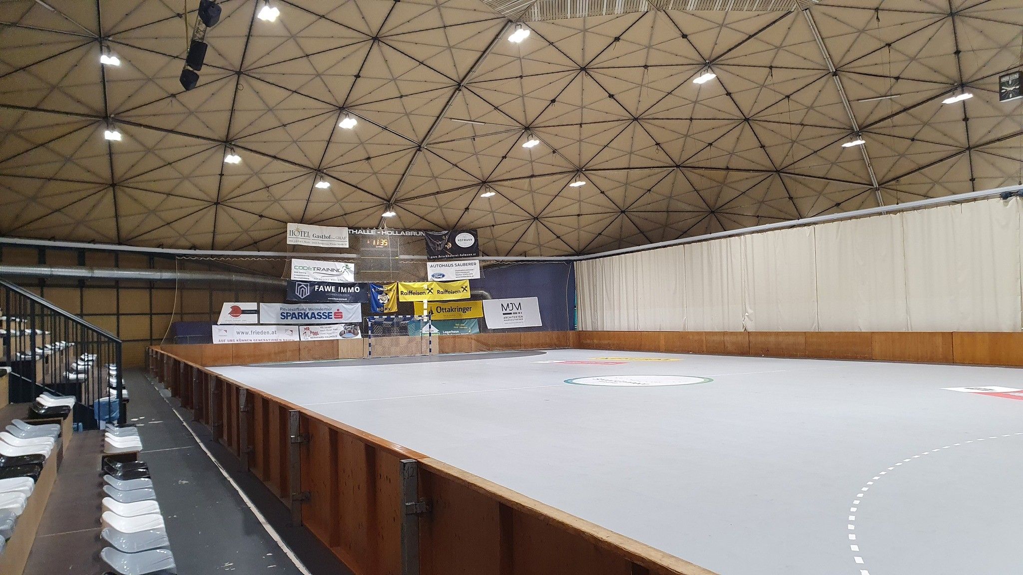 Innenansicht der Sporthalle Hollabrunn mit leeren Tribünen und Spielfeld.
