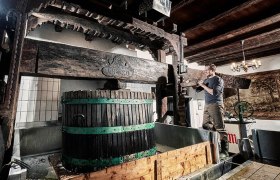 Ein Mann arbeitet an einer traditionellen Weinpresse in einem Weingut.