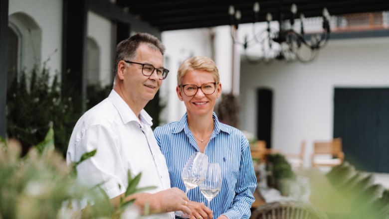 Zwei Personen stehen draußen und halten Weingläser.