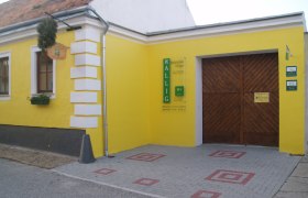 Gelbes Geb&auml;ude mit Holztor und Schild 'Wallig'.