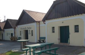 Traditionelle Weinkeller mit Holzbänken und Tischen im Freien.