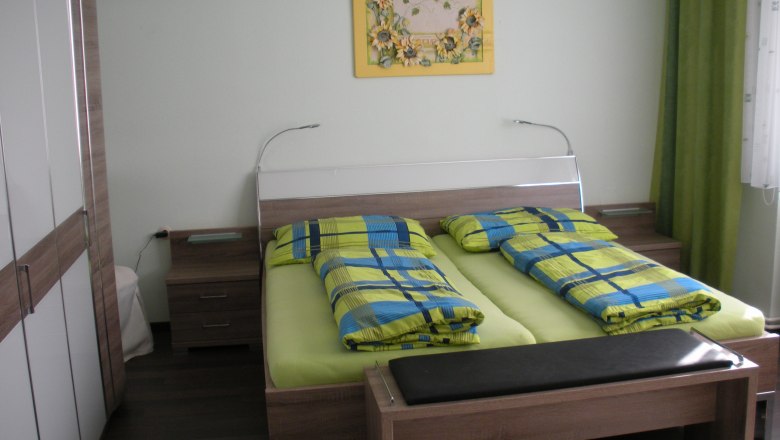 Gästezimmer, © Familie Gartner Gästezimmer mit Doppelbett, bunter Bettwäsche und Wandbild.