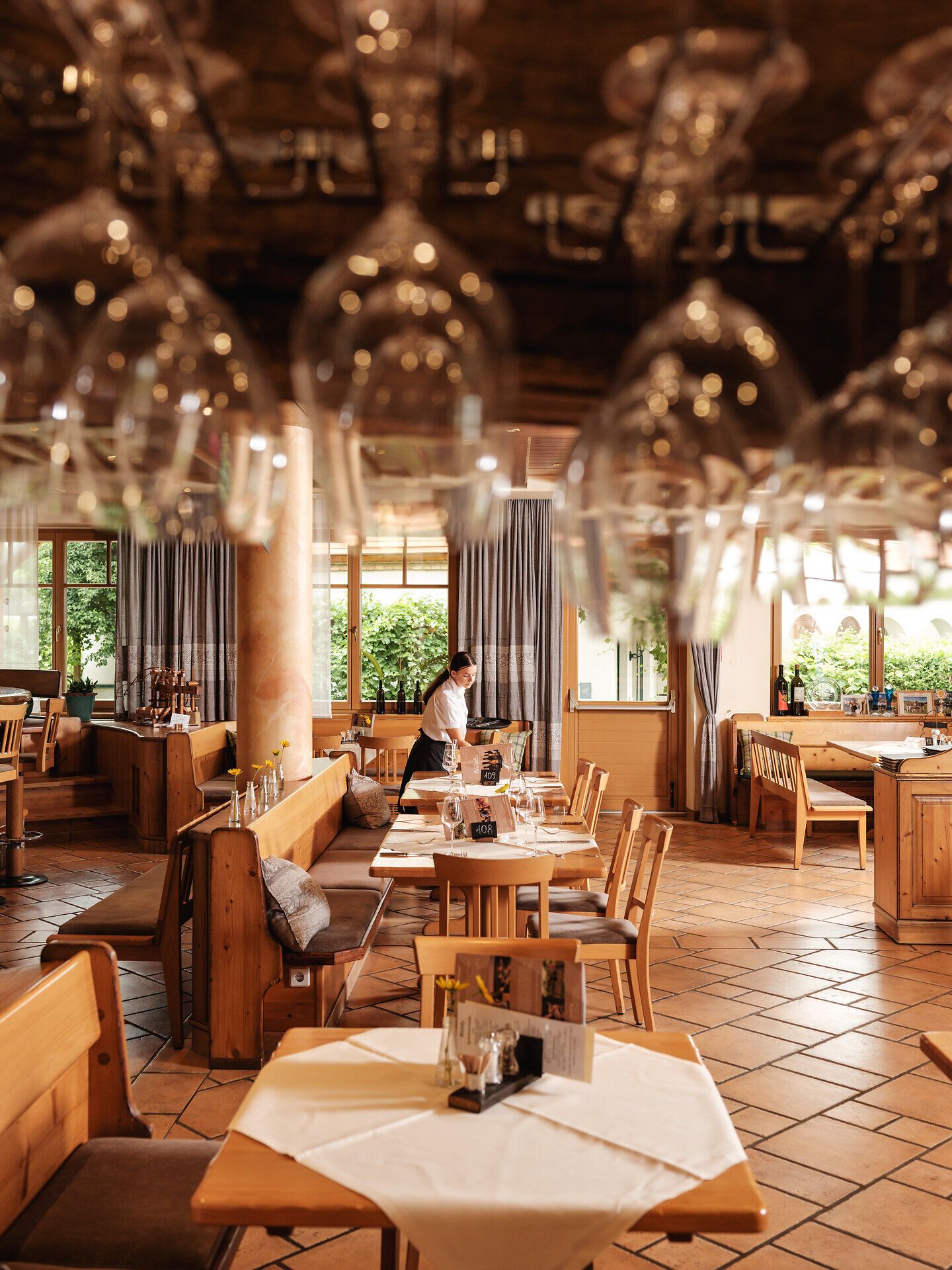 In einem einladenden Restaurant, umgeben von warmem Holz und sanftem Licht, genießen Gäste die kulinarischen Köstlichkeiten der Region. Die Atmosphäre ist geprägt von der Vorfreude auf den Weinleseherbst, während die Gläser schimmern und die Tische liebevoll gedeckt sind.