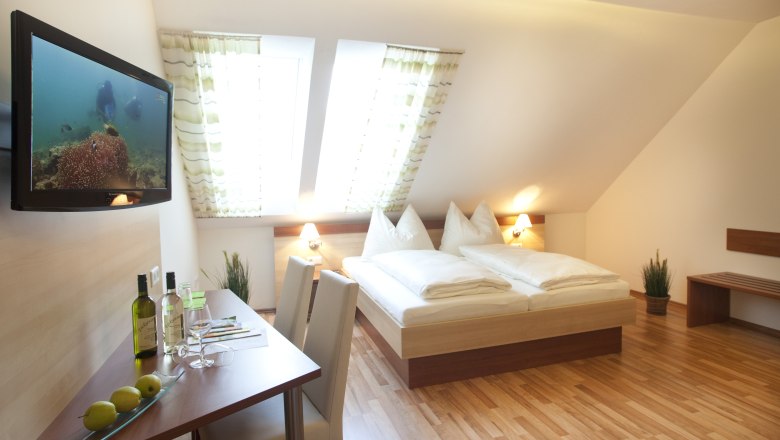 Guest room, © Astrid Bartl A cozy guest room with double bed, flat screen TV, table with chairs and skylights.