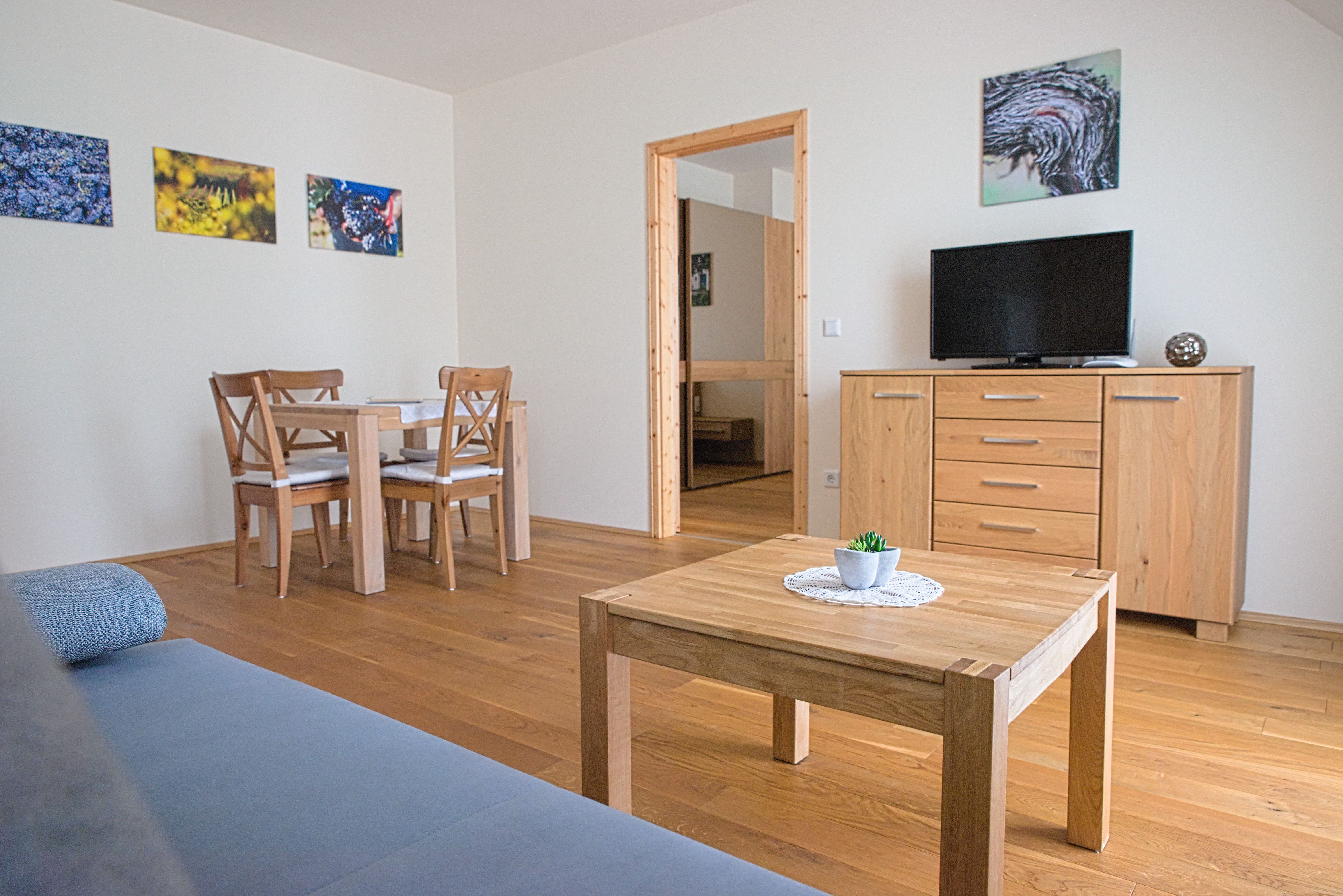 Ein modernes Gästezimmer mit Holzmöbeln, einem Tisch, Stühlen, einem Fernseher und Wandbildern.