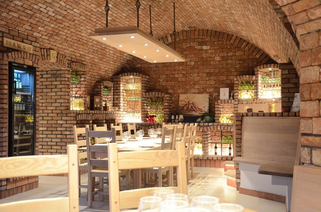 Cozy wine cellar with brick walls, wooden tables and chairs, illuminated wine rack and decorative elements.