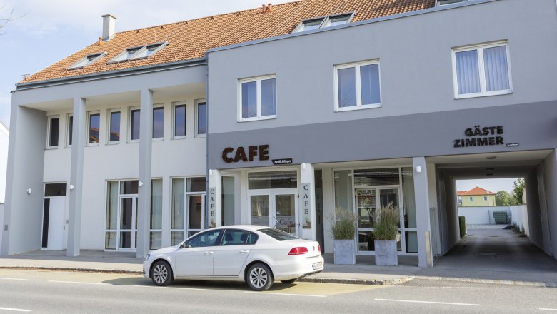 Exterior view of a gray building with a café and guest rooms.