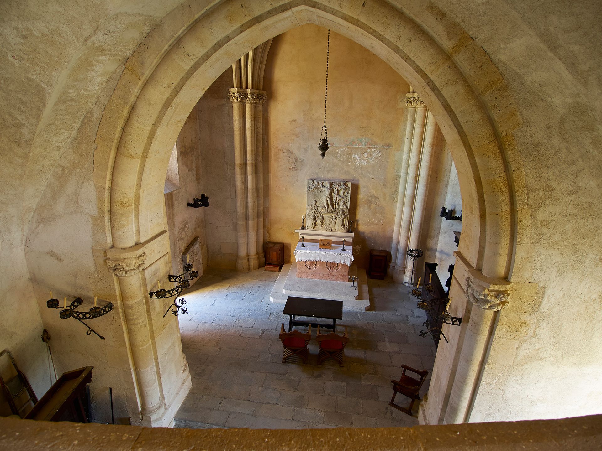 Innenansicht einer historischen Kapelle mit Altar und gotischen Bögen.