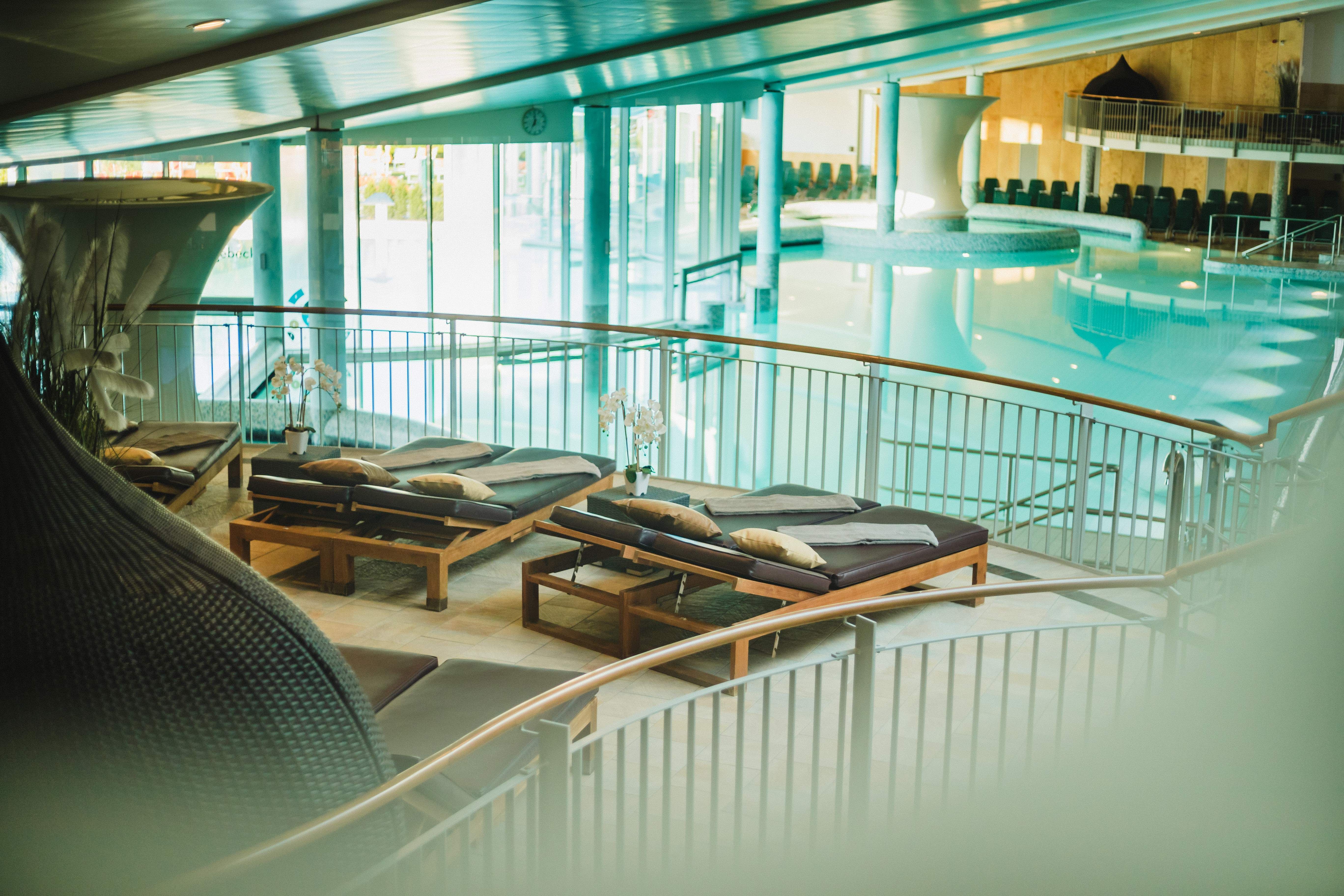 Innenansicht eines modernen Spas mit Liegestühlen und einem großen Pool.