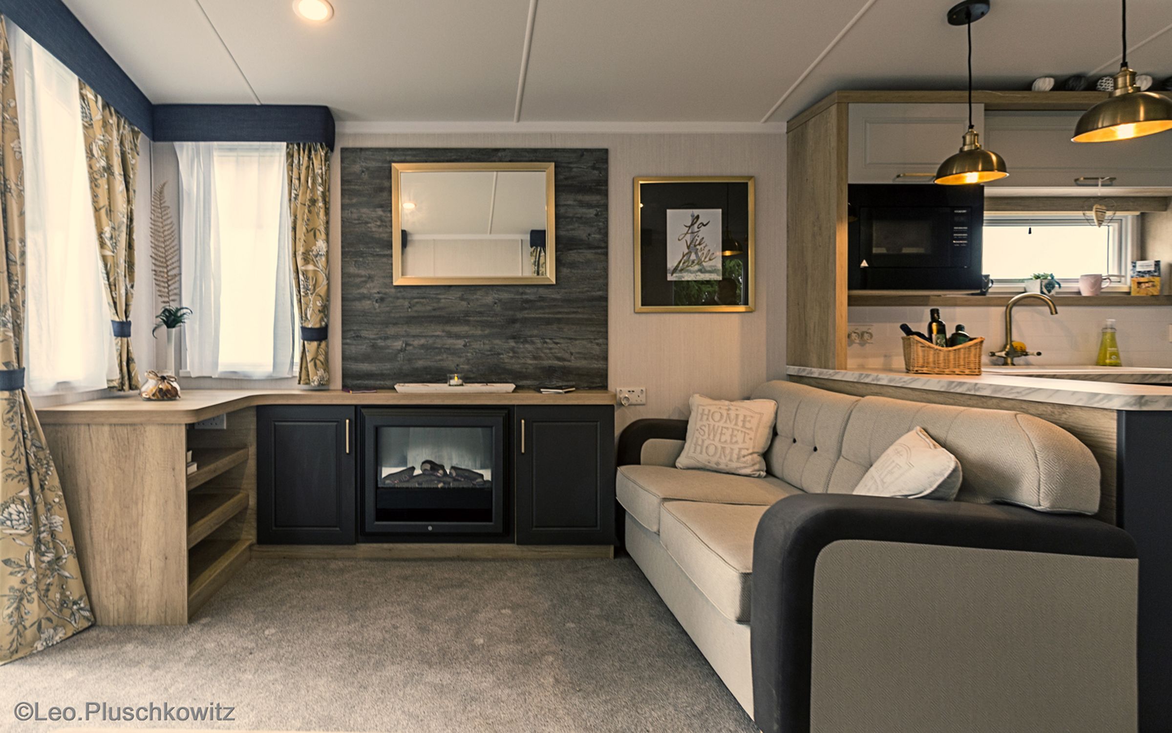 Gemütliches Wohnzimmer mit Sofa, Kamin, Spiegel und Küche.