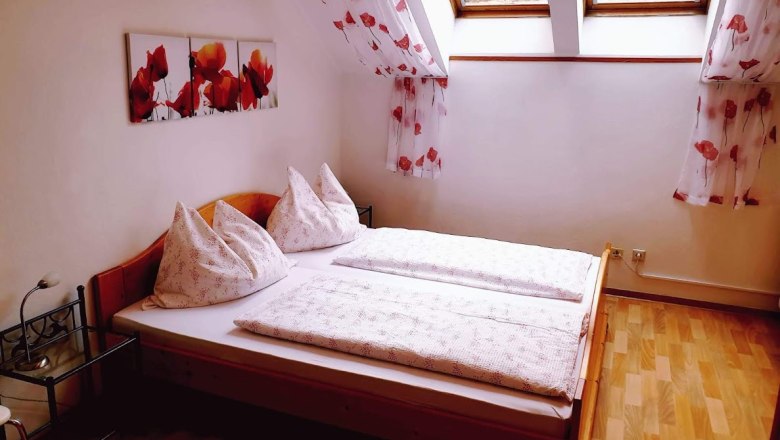 Gem&uuml;tliches Schlafzimmer mit Doppelbett, Dachfenstern und Mohnblumen-Dekor.