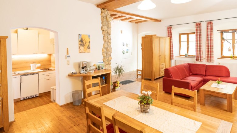 Gemütliches Wohnzimmer mit Holzmöbeln, rotem Sofa und offener Küche.