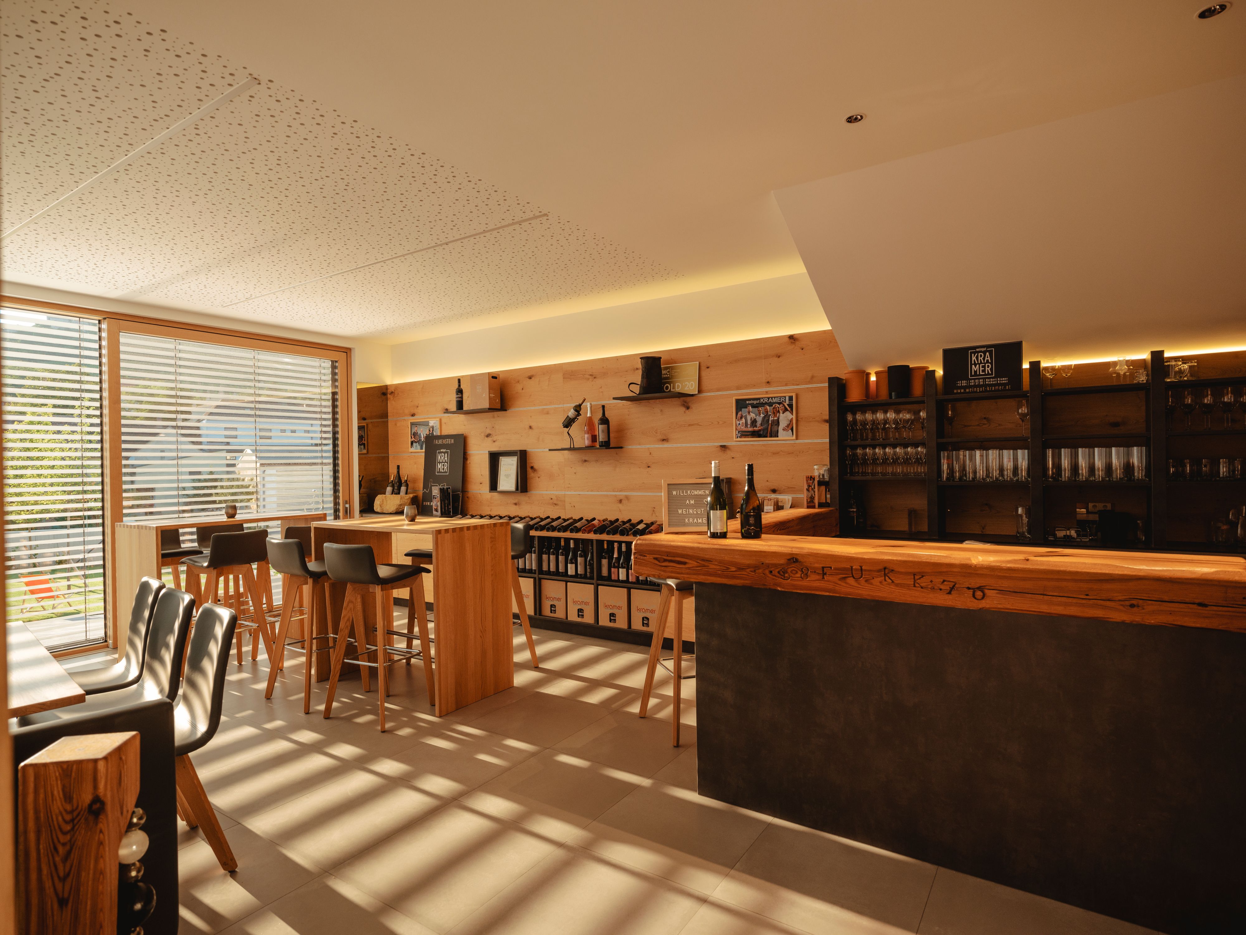 Interior view of a modern wine bar with wooden furniture and large windows.