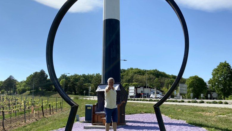 A man stands behind a large key shape in Maissau, with a sign for the Wine Road Weinviertel in the background.