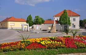 Blumenbeet und Skulptur auf dem Hauptplatz von Mailberg.