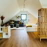 Gemütliches Dachgeschoss-Apartment mit Sofa, Bett und Holzboden.