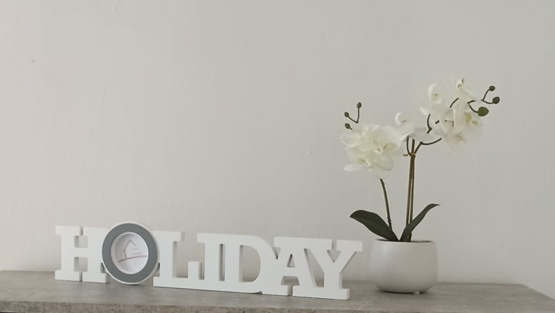 A warm welcome, © Multimedia Lauda Decoration with 'HOLIDAY' lettering and white orchid in a pot on a table.