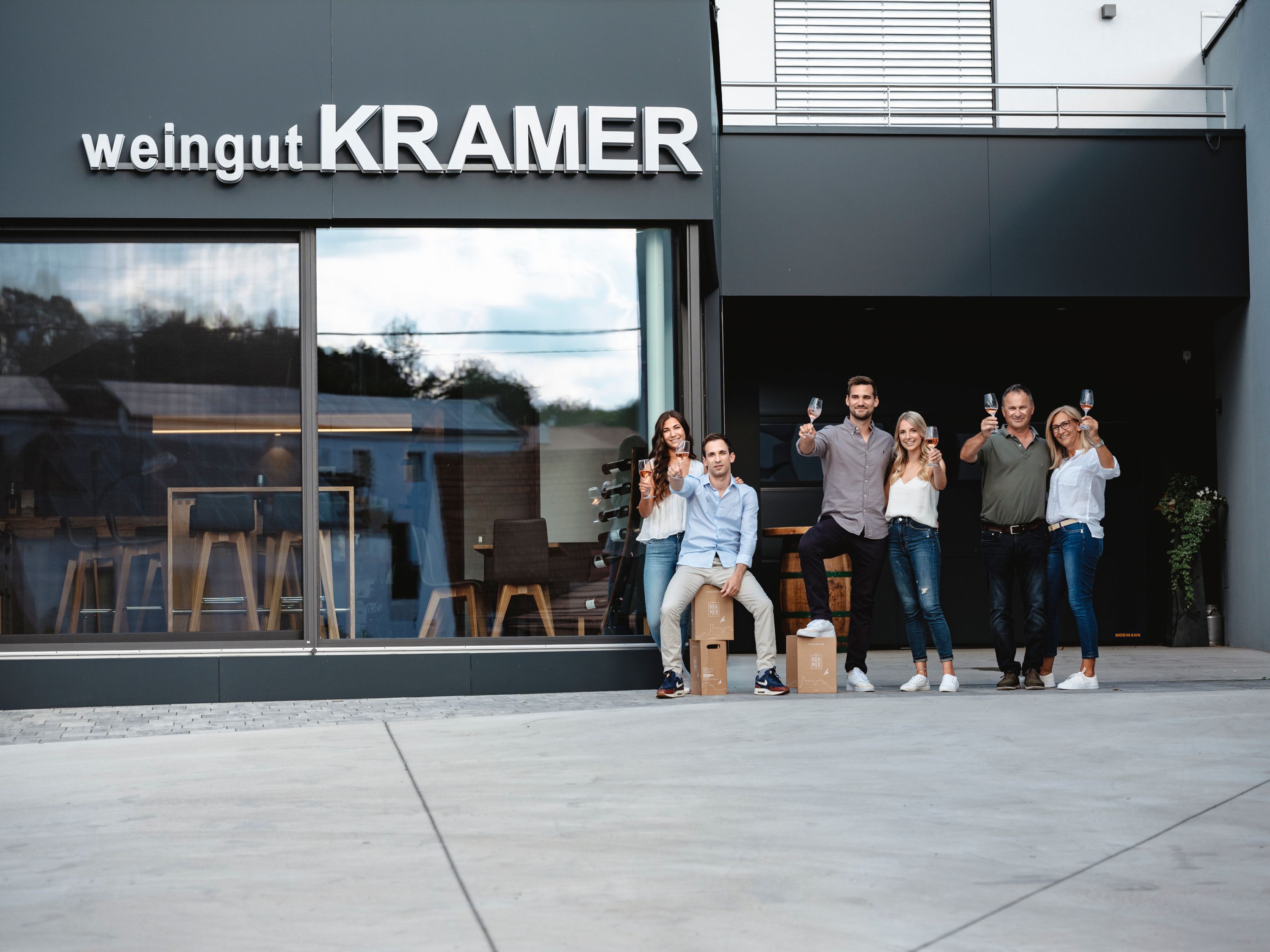 Group of people in front of a winery with glasses in their hands.
