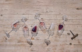 Umgekippte Weingläser mit Rotwein auf Holztisch.