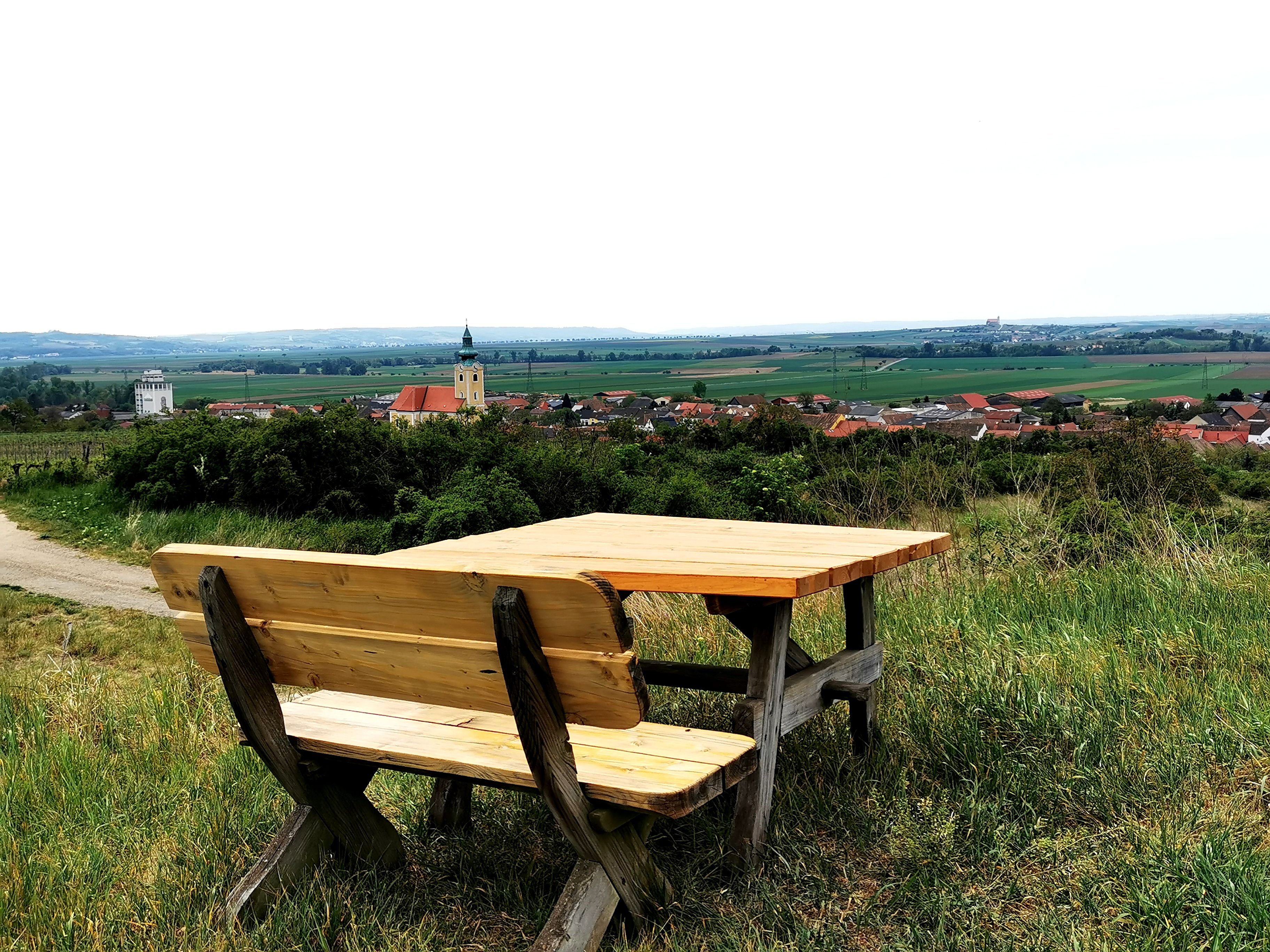 Drevená lavička so stolom na kopci s výhľadom na Röschitz a okolitú krajinu.