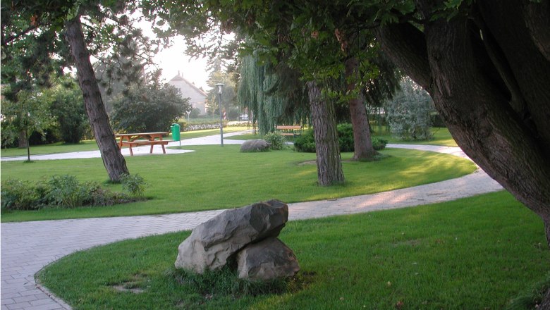Ein gepflegter Park mit Bäumen, Wegen und Bänken.