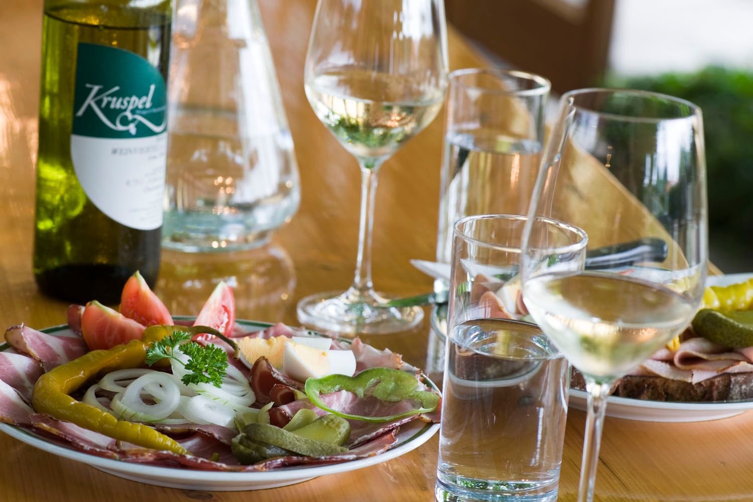 Ein gedeckter Tisch mit Heurigenjause, Wein und Wasser.
