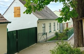 Ein traditionelles, weißes Ferienhaus mit grünem Zaun und Baum im Vordergrund.