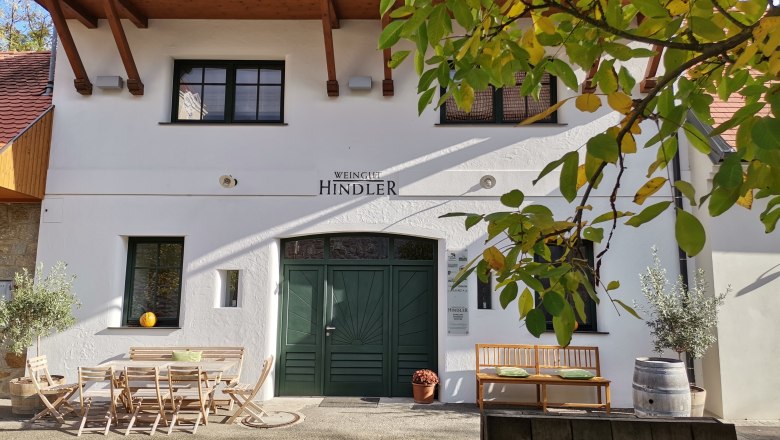 Entrance to a winery with wooden furniture and plants.