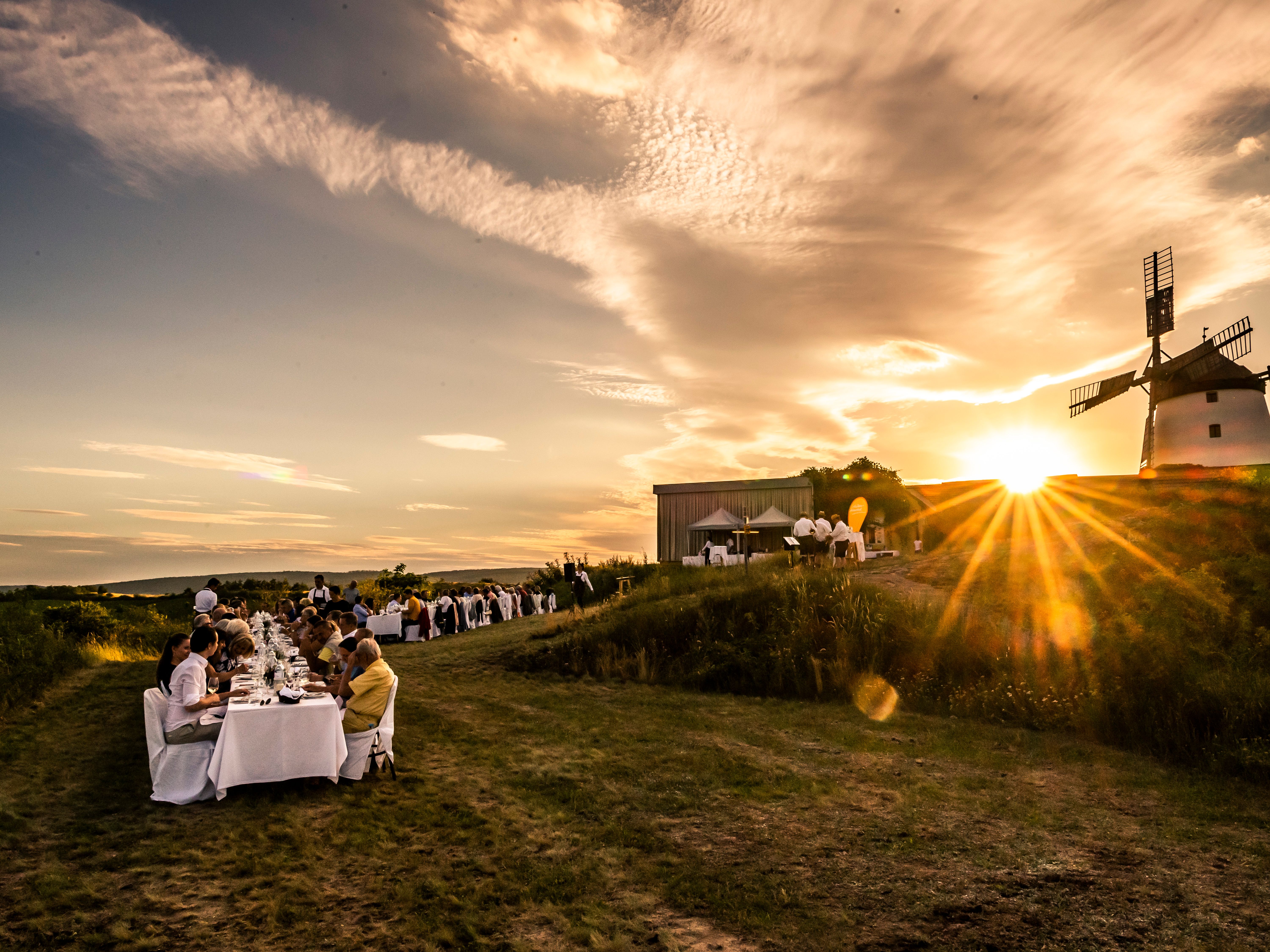Abendessen im Freien bei Sonnenuntergang mit Windmühle im Hintergrund.