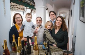 Familie sitzt an einem Tisch mit Sektflaschen und Gl&auml;sern.
