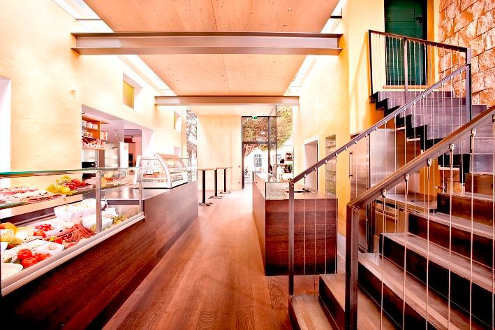 Innenansicht eines modernen Buffets mit Holzboden, Treppe und Glasvitrinen.