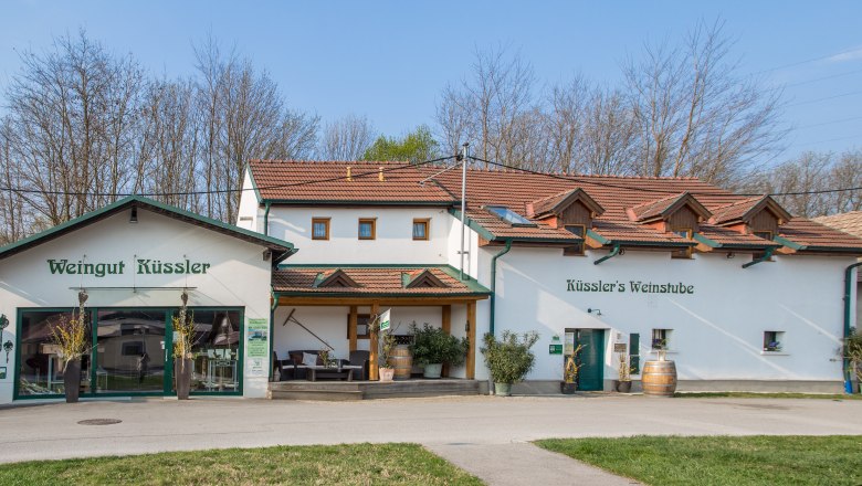Weingut Küssler mit Weinbar und Terrasse, umgeben von Bäumen.