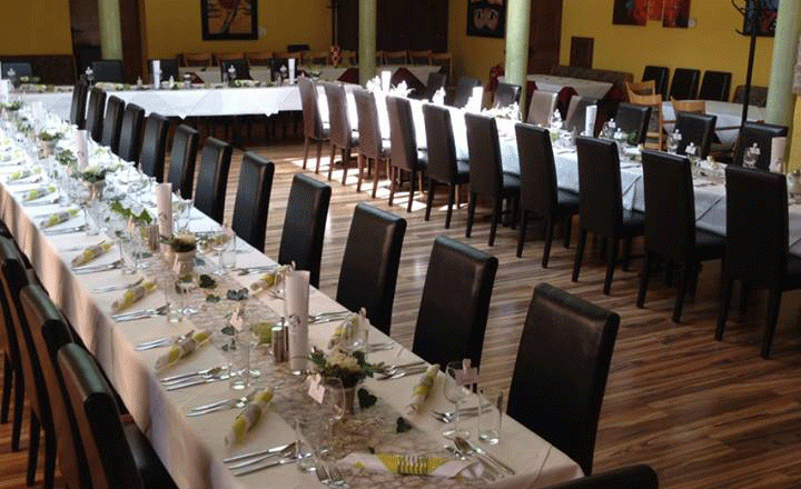 Festlich gedeckte Hochzeitstafel in einem Raum mit gelben Wänden und Backsteinbögen.