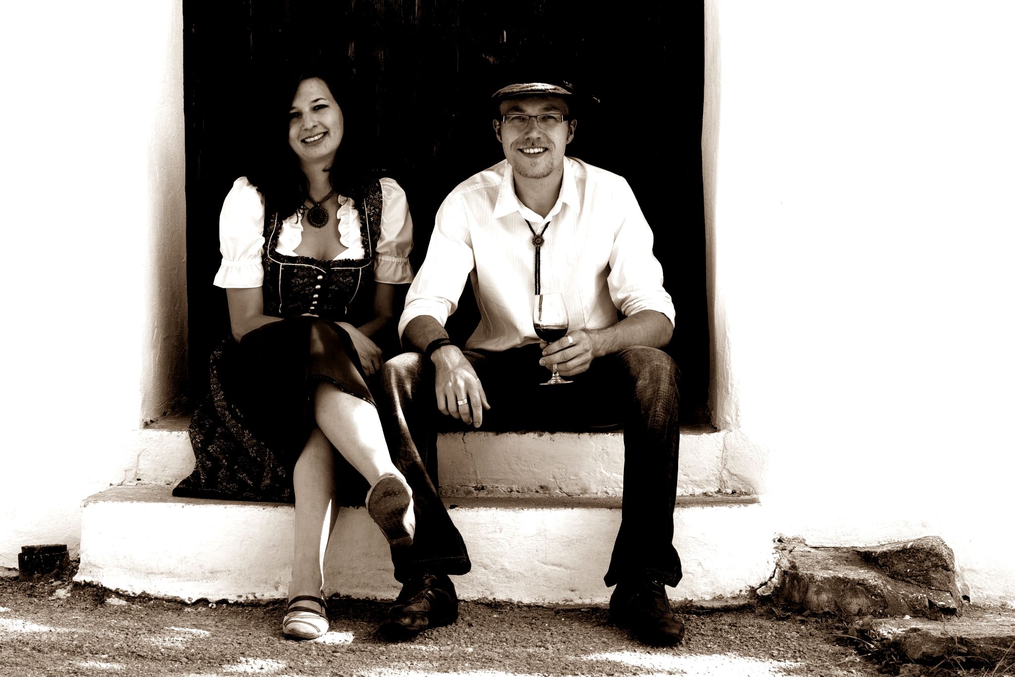 Ein Mann und eine Frau sitzen auf einer Treppe, der Mann hält ein Weinglas.