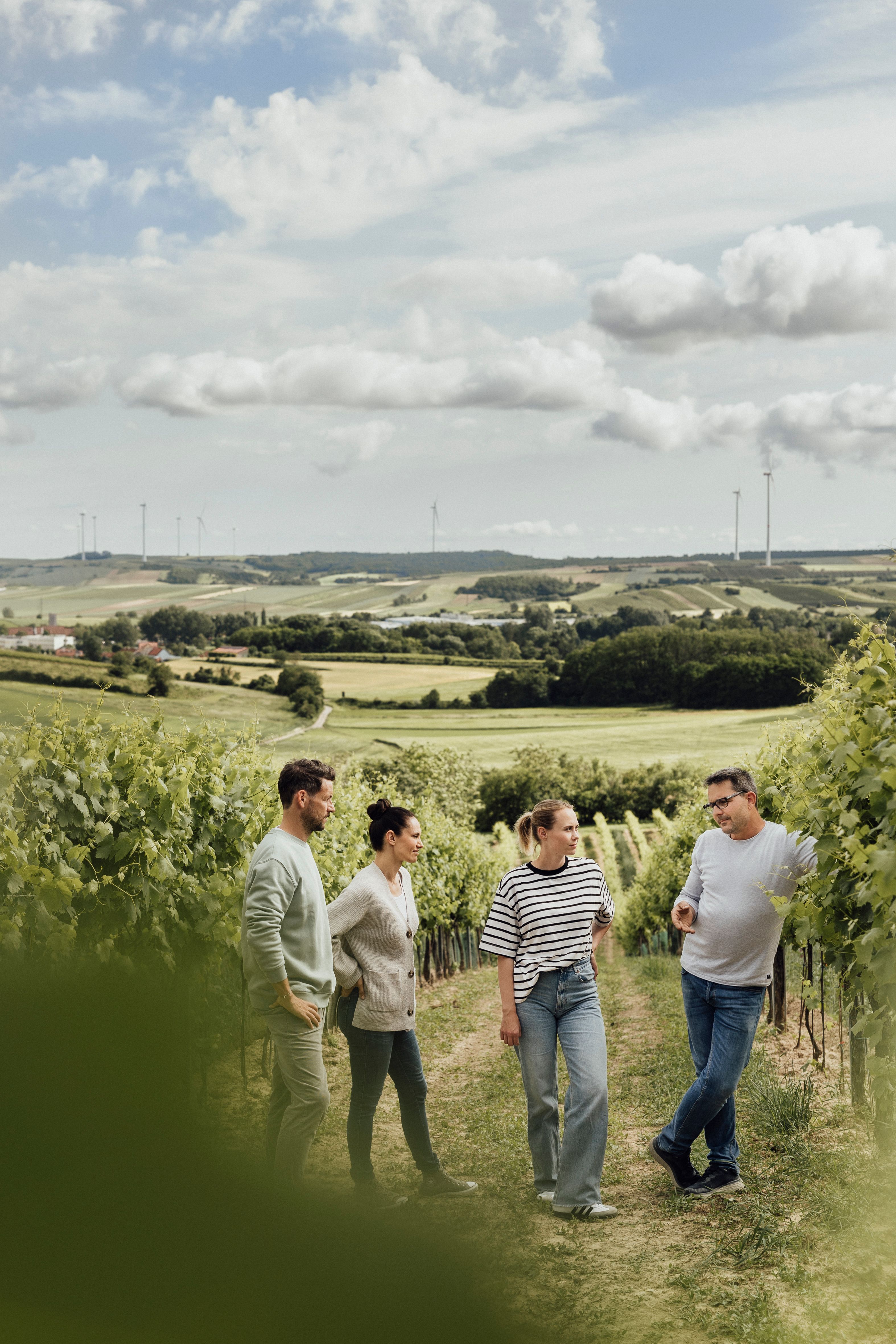 Inmitten der sanften Hügel und üppigen Weinreben genießen Freunde einen entspannten Spaziergang. Die frische Luft und die malerische Landschaft laden dazu ein, die Seele baumeln zu lassen und die köstlichen Weine der Region zu verkosten. Ein perfekter Tag für Weinliebhaber und Naturliebhaber gleichermaßen.