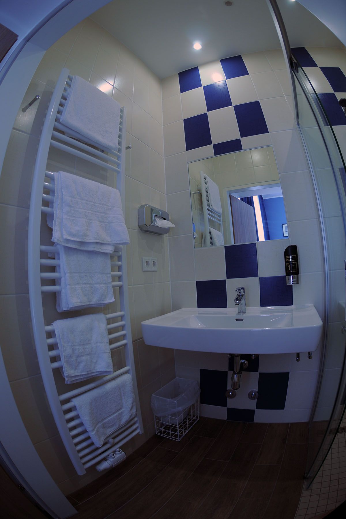 Modernes Badezimmer mit blau-weißen Fliesen, Waschbecken, Handtuchhalter und Spiegel.