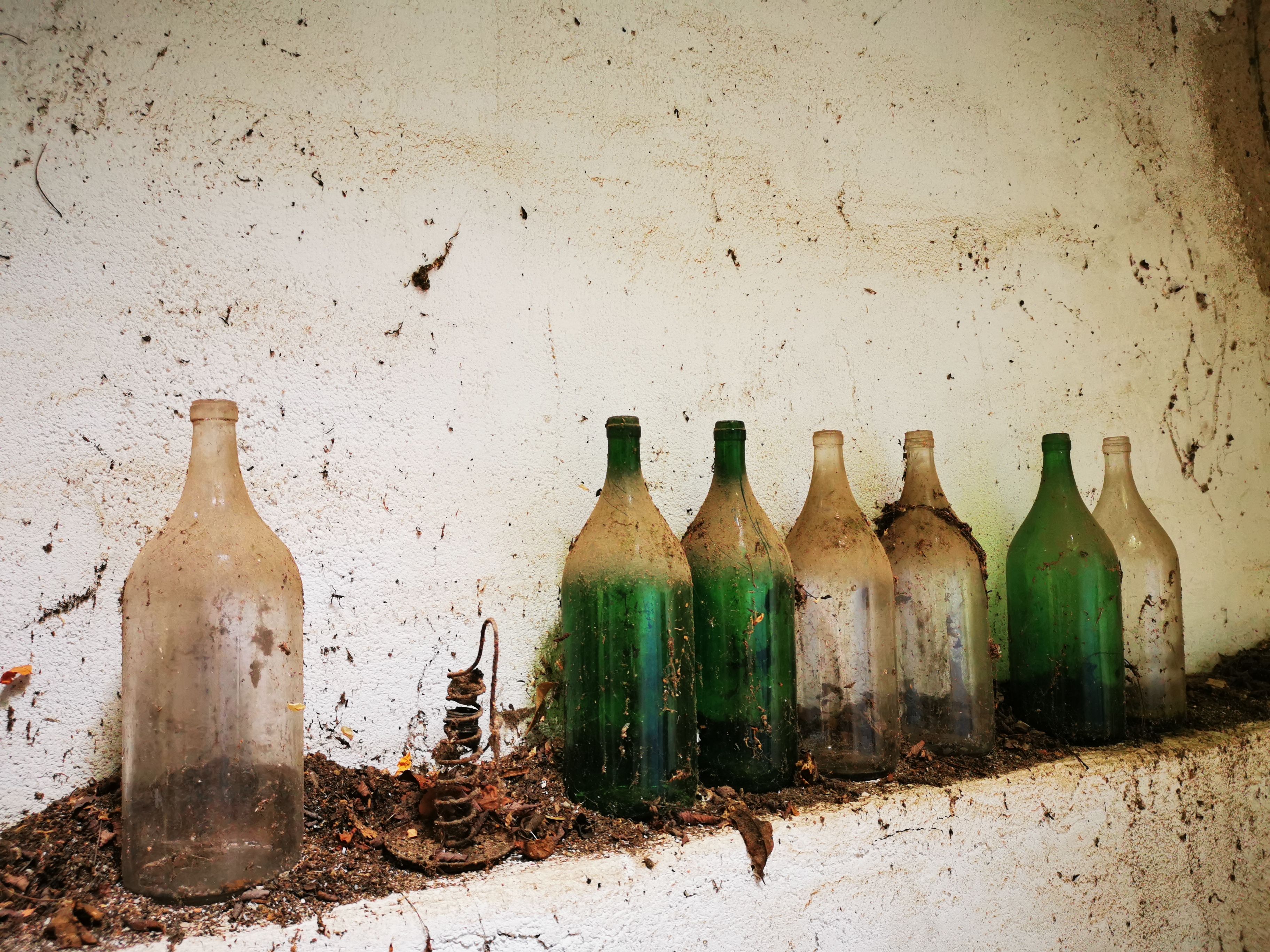 Old, dusty glass bottles on a shelf in a cellar.