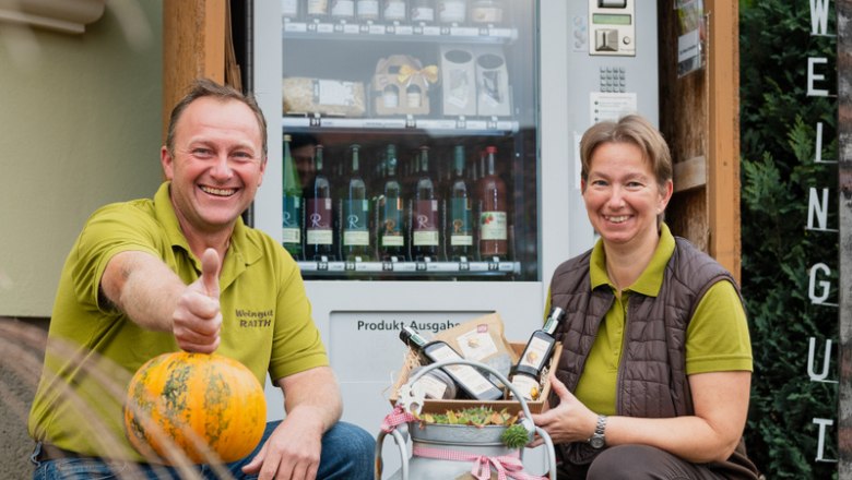 Two people in front of a self-service vending machine with pumpkins and regional products.