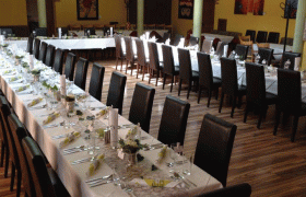 Festlich gedeckte Hochzeitstafel in einem Raum mit gelben Wänden und Backsteinbögen.