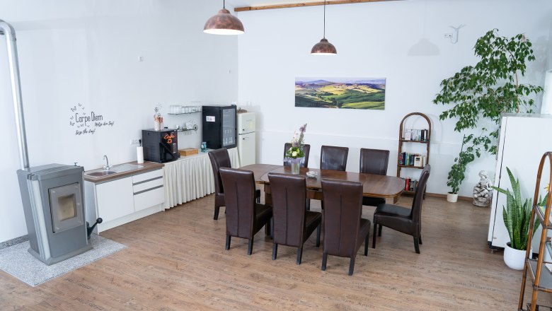 Gemütlicher Raum mit Esstisch, Stühlen, Pflanzen und Küchenzeile.