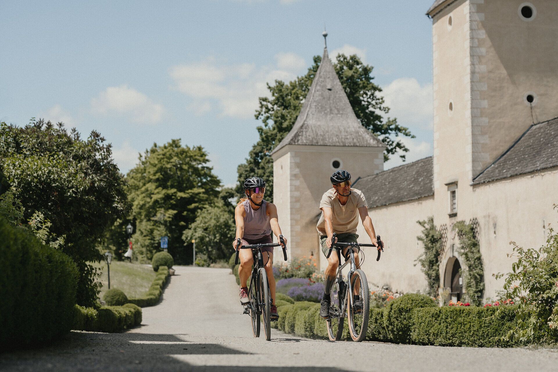 Zwei Radfahrer auf einer Straße vor Schloss Rosenburg.