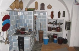 Historische Küche im Südmährermuseum mit blau gekacheltem Ofen und traditionellen Küchenutensilien.