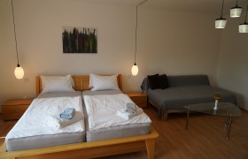 Gemütliches Schlafzimmer mit Doppelbett, Sofa und Glastisch.