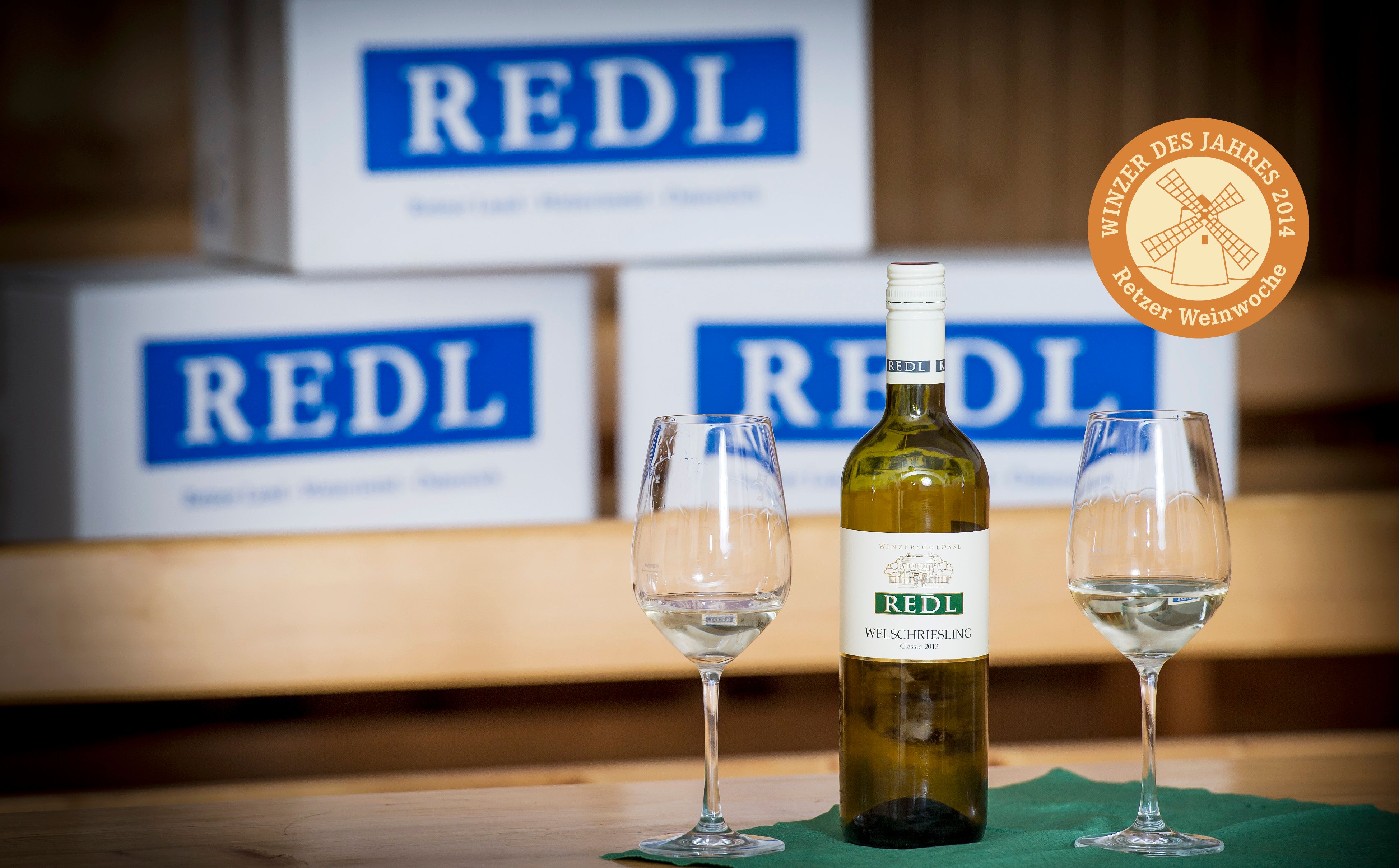 Wine bottle and glasses in front of Redl cartons.
