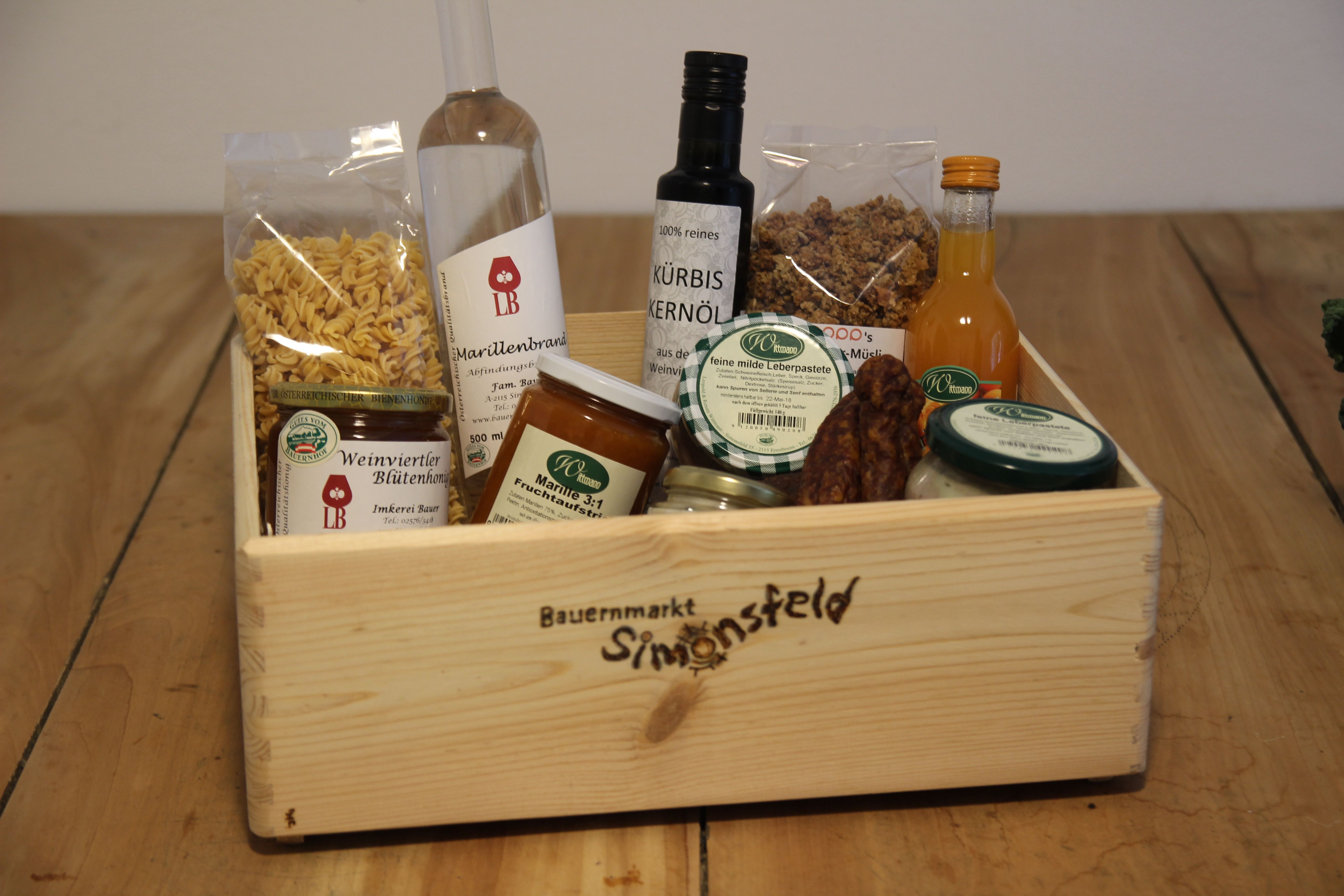 Holzkiste mit regionalen Produkten wie Öl, Honig, Marmelade und Pasta.