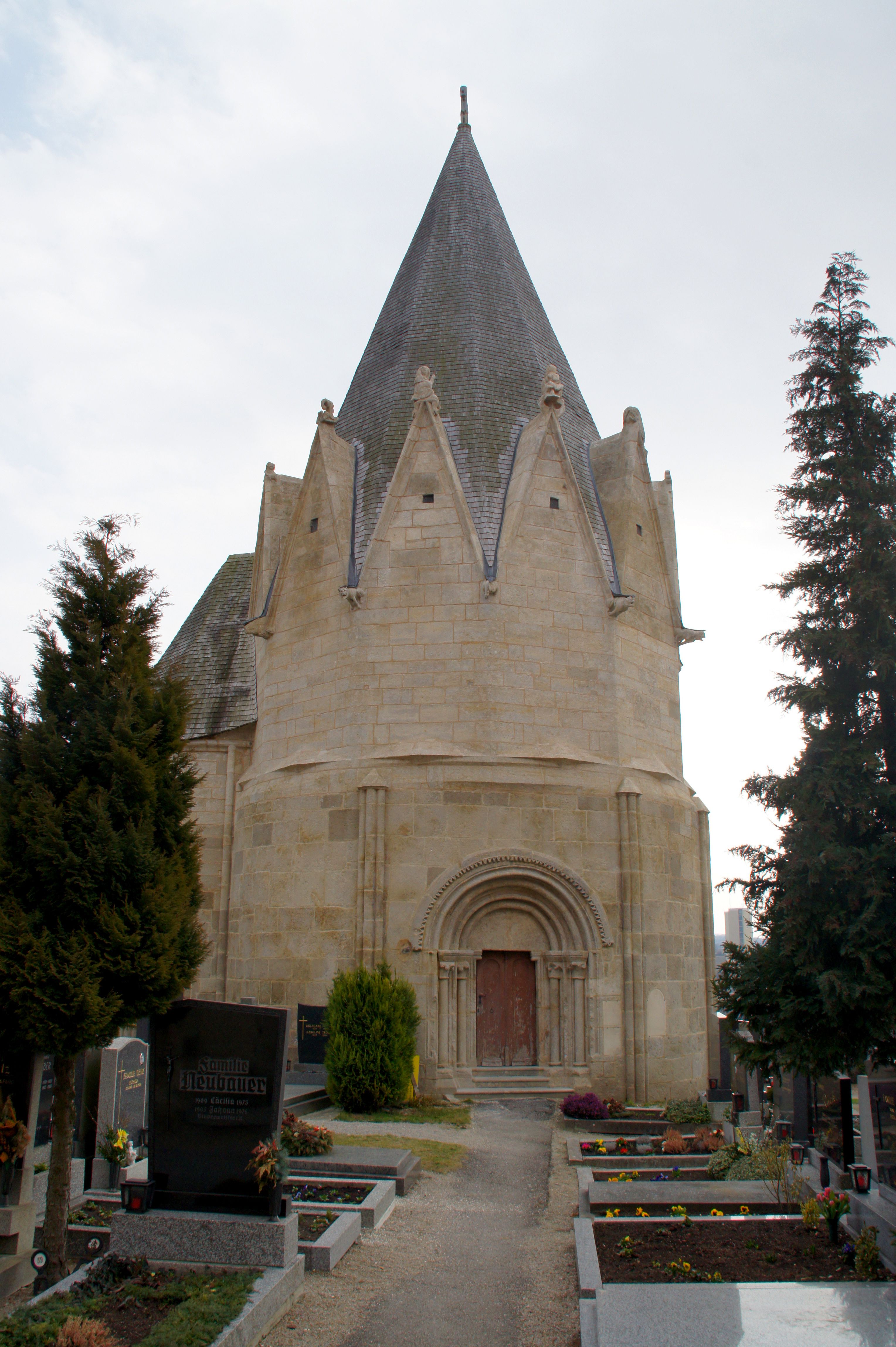 Karner Pulkau, ein historisches Gebäude mit spitzem Dach, umgeben von einem Friedhof.