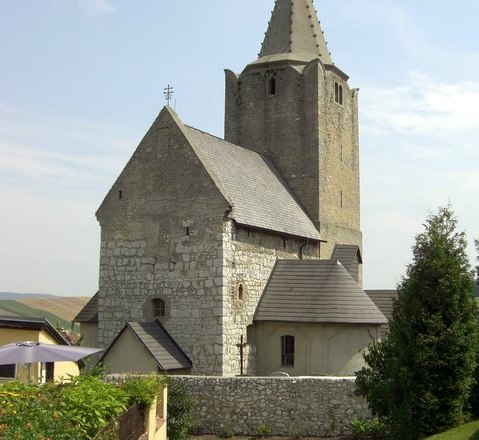 Historische Wehrkirche mit steinernem Turm und Spitzdach.